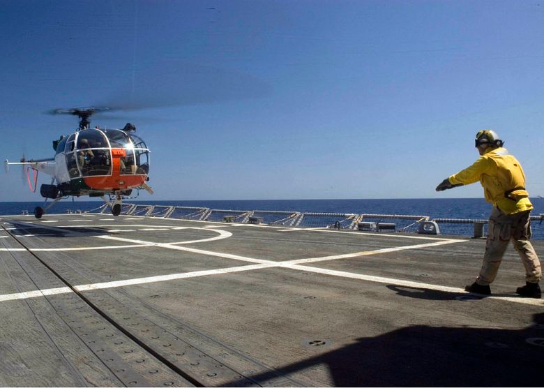 A chief Boatswain directs an Armed Forces of Malta Alouette helicopter to a landing aboard the guided-missile frigate USS Robert G. Bradley (FFG 49). Photograph is part of the Public Domain.